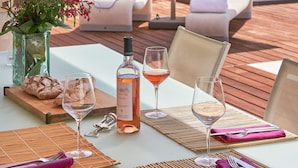 A table set for dining outdoors with a bottle of wine, glasses, and a loaf of bread. - SunlightProperties: SPLENDID: Villa, 4 Bedroom/ 3 bath, jacuzzi, heated pool (Peymeinade)
