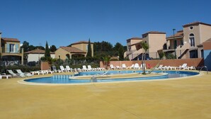 A pool area with multiple lounge chairs and a clear blue sky.