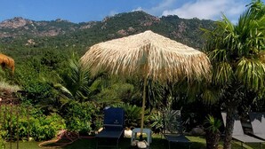 A pool area with lounge chairs, a thatched umbrella, and a view of mountains. - If you like peace and quiet between sea and mountains (Zonza)