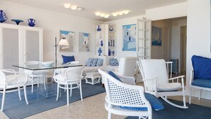 A modern living room with white furniture, a glass coffee table, and blue accents. - UHC Piscis Apartments: Seafront Stay with Sea Views (Salou)