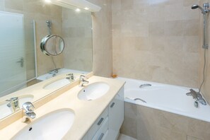 Une salle de bain avec deux lavabos, un miroir et une douche.