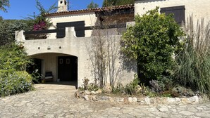 A rustic building with a stone archway entrance, a tiled roof, and a garden with various plants. - 5mn from beaches, Villa with swimming pool in Hyères, large garden. (Hyeres)