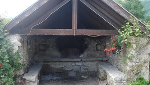 A stone structure with a wooden roof, possibly a historical building or a rustic shelter.