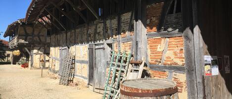 A rustic building with a wooden exterior, a brick wall, and a wooden barrel in front.