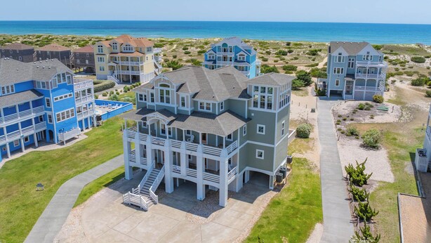 A coastal residential area with multi-story houses featuring balconies and a view of the ocean.