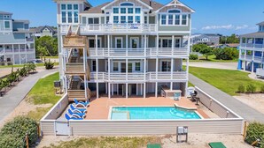 A multi-story beachfront property with a pool, balconies, and a covered patio.