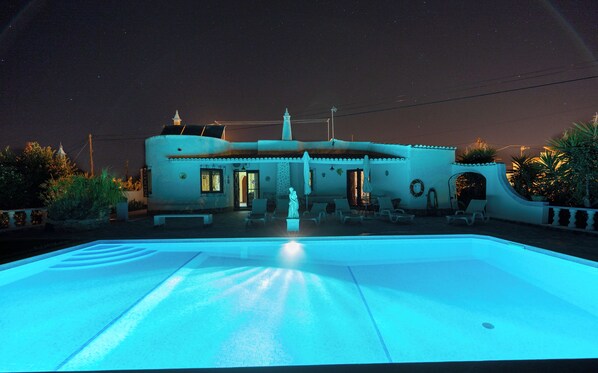 A swimming pool with a unique architectural design, a statue in the center, and a night sky. - Villa 10 minutes from the beach, in a very quiet location w/ private pool (Armação de Pêra)