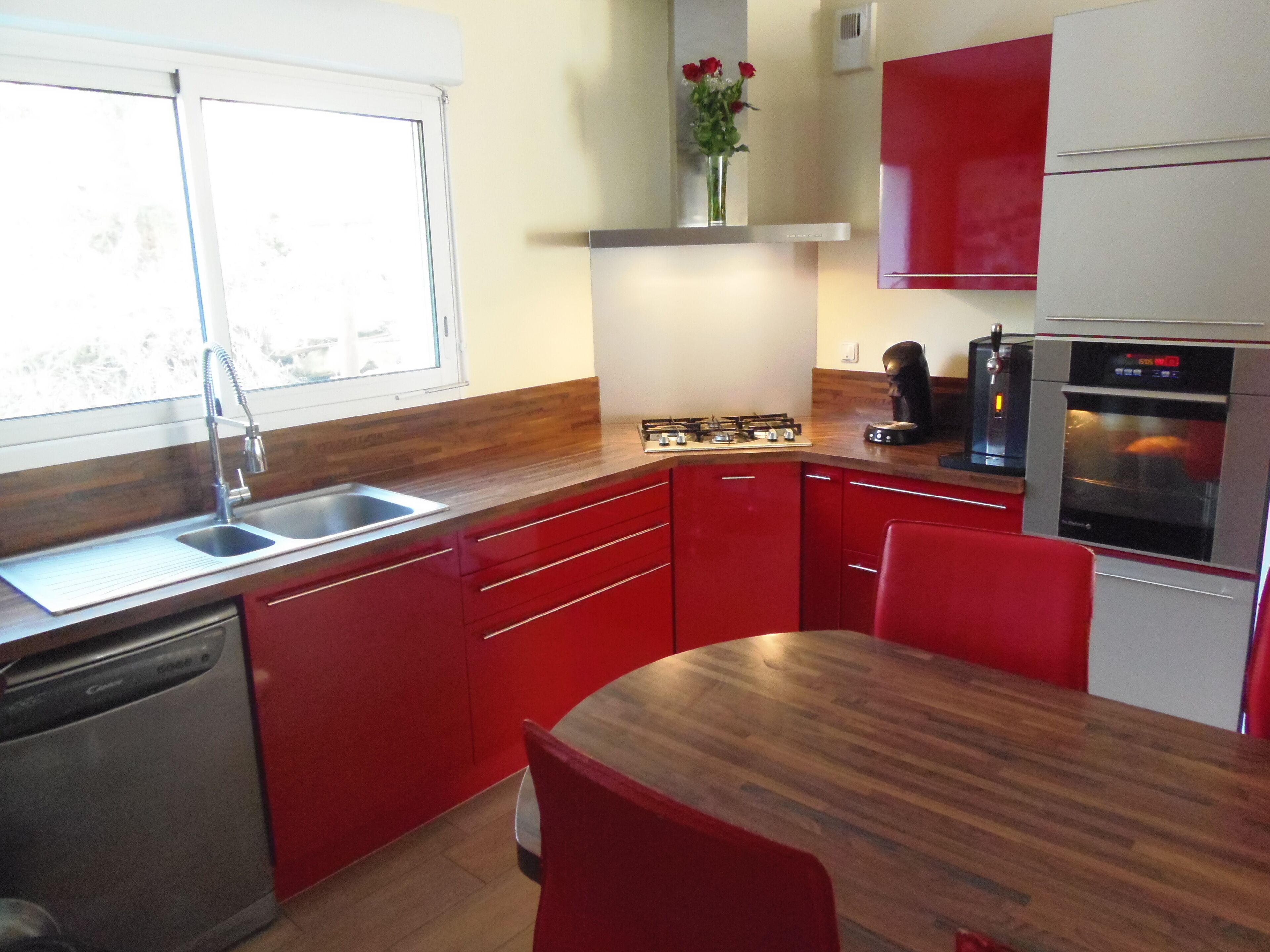 Una cocina con armarios rojos, encimera de madera, un lavabo, una estufa y un horno.