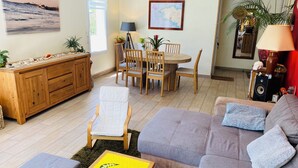 Una sala de estar acogedora con un sofá, una mesa de comedor con sillas, un aparador de madera y un cuadro en la pared.