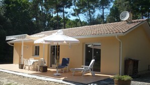 A single-story house with a tiled roof, a patio with outdoor furniture, and a satellite dish. - Le Verdon Sur Mer: House / Villa - Soulac / Le Verdon sur Mer (Le Verdon-sur-Mer)