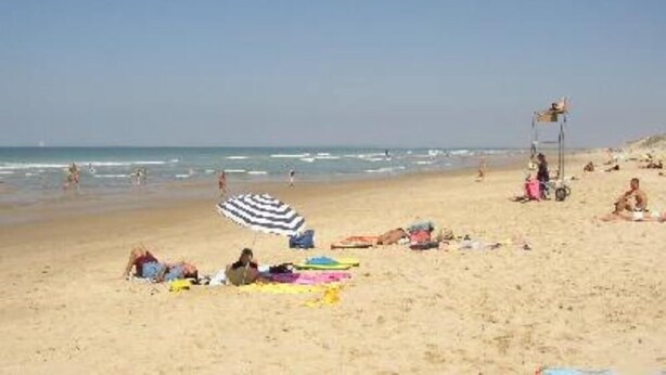 A beach with people sunbathing and swimming. There are umbrellas and beach towels on the sand. - Le Verdon Sur Mer: House / Villa - Soulac / Le Verdon sur Mer (Le Verdon-sur-Mer)