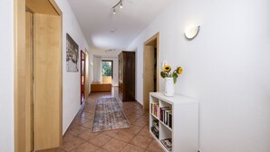 A hallway with a wooden door, a bookshelf with books, a vase with flowers, and a rug. - Large apartment: sunny, bright and quiet - modern - with a great view  (Ramsau im Zillertal)