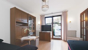 Um espaço de estar compacto com sofá, televisão, armário de madeira e janela com cortinas.