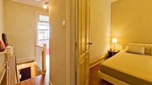 A hotel room with a bed, a nightstand, a lamp, and a view of the outside. - Porto, City Center Apartment - Right in the Heart of the City! (Porto)