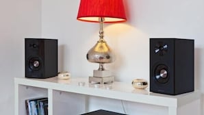 A white shelf with two black speakers, a red lamp, and decorative glass spheres. - Porto, City Center Apartment - Right in the Heart of the City! (Porto)