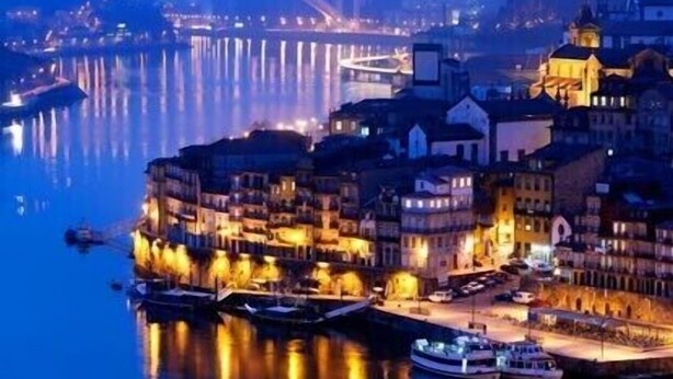 A waterfront cityscape at night with illuminated buildings and boats docked along the river. - Porto, City Center Apartment - Right in the Heart of the City! (Porto)