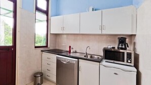 A compact kitchen with white cabinets, a stainless steel dishwasher, a sink, and a microwave. - Porto, City Center Apartment - Right in the Heart of the City! (Porto)