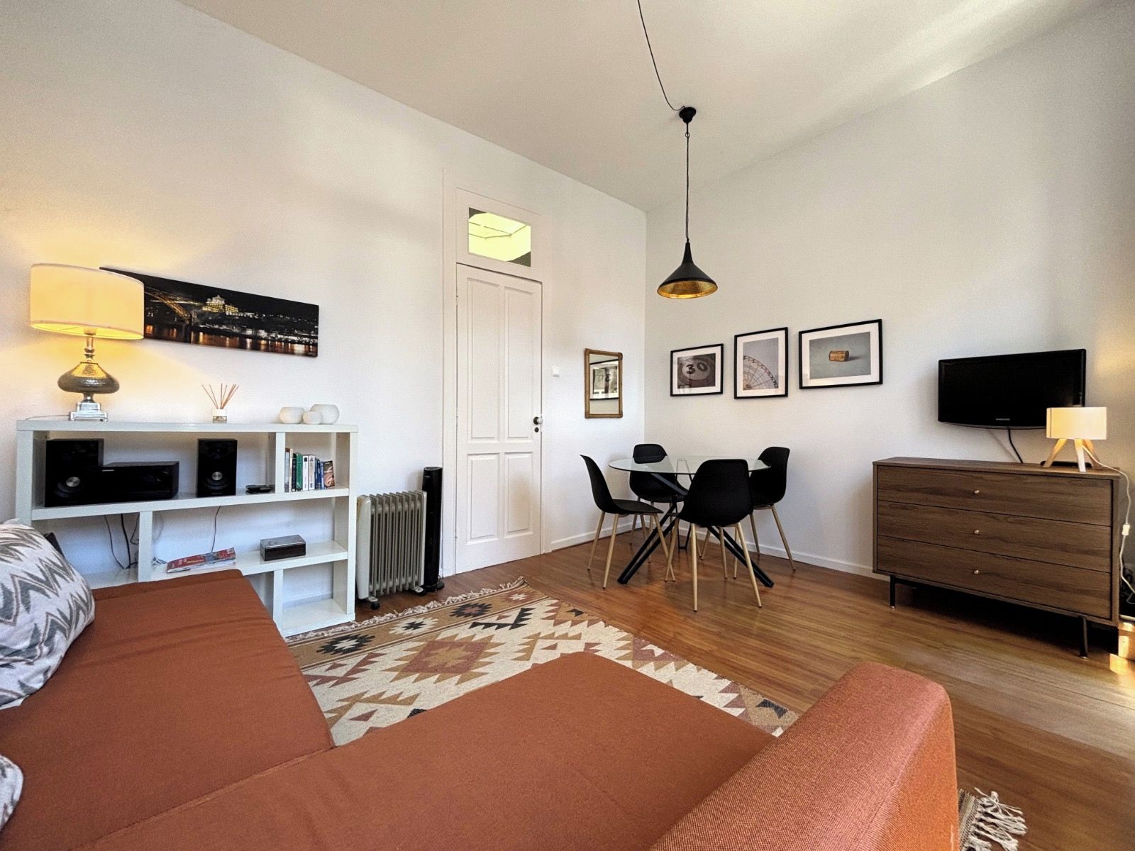 Een moderne woonkamer met een bank, een eettafel met stoelen, een televisie en een open haard.