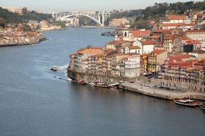 A riverside cityscape with historic buildings, a bridge, and boats docked along the waterfront. - Porto, City Center Apartment - Right in the Heart of the City! (Porto)
