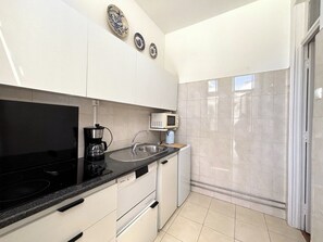 A modern kitchen with white cabinets, a black countertop, a coffee maker, a microwave, and a sink.