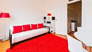 A modern living room with a white sofa, red cushions, a red rug, a white table, and a red lamp. - Porto, City Center Apartment - Right in the Heart of the City! (Porto)