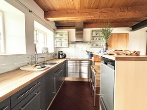 A modern kitchen with stainless steel appliances, wooden countertops, and a built-in dishwasher.