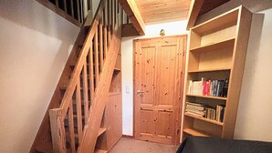Un escalier en bois menant  à une porte, une bibliothèque remplie de livres et un sol recouvert d’une moquette.