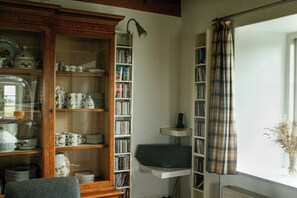Una habitación con un armario de madera que contiene vajilla y una estantería llena de libros.
