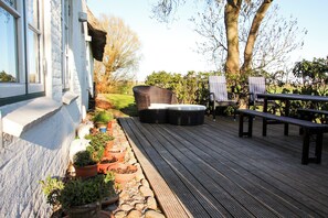 Eine Holzterrasse mit Gartenmöbeln, Blumentöpfen und einem Gartenbereich.