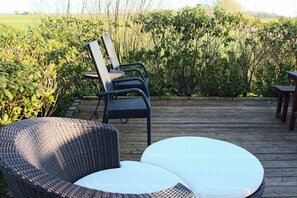 Un área de estar al aire libre con mobiliario de mimbre y una terraza de madera.