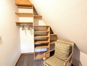 A corner of a room with a wooden chair, a built-in wooden shelf unit, and a small area rug.