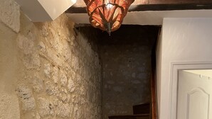A wooden staircase with a stone wall on one side and a white door on the other.
