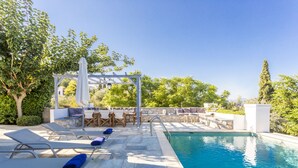 Ein Poolbereich mit Liegestühlen, einer Pergola und einem Essbereich.