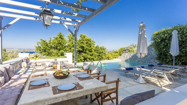 Ein Essbereich im Freien mit Pool, Sitzgelegenheiten und einer Pergola.