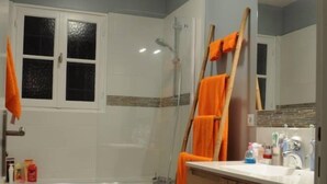 Ein Badezimmer mit einer Badewanne, einem Holzkosmetikschrank, einem Spiegel und einer Duschkabine.