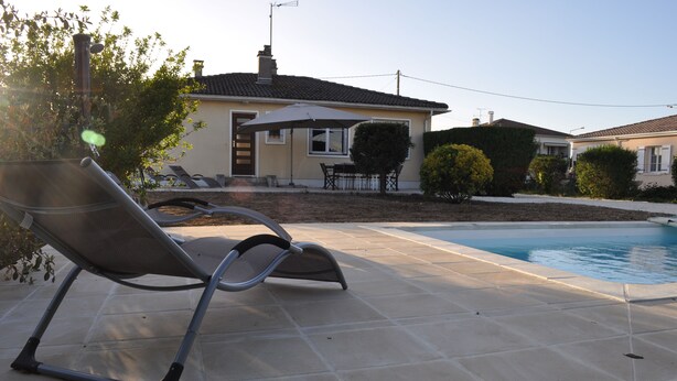 Ein Poolbereich mit Liegestühlen und einem Haus im Hintergrund.