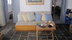 A cozy room with a plaid sofa, a small wooden table with a bowl and a cup, and a framed picture of a sailboat on the wall. - Artemonas: House with character (Artemonas)