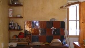 A compact kitchen with wooden cabinets, a tiled backsplash, and a window providing natural light. - country holiday home - BARREME (Clumanc)