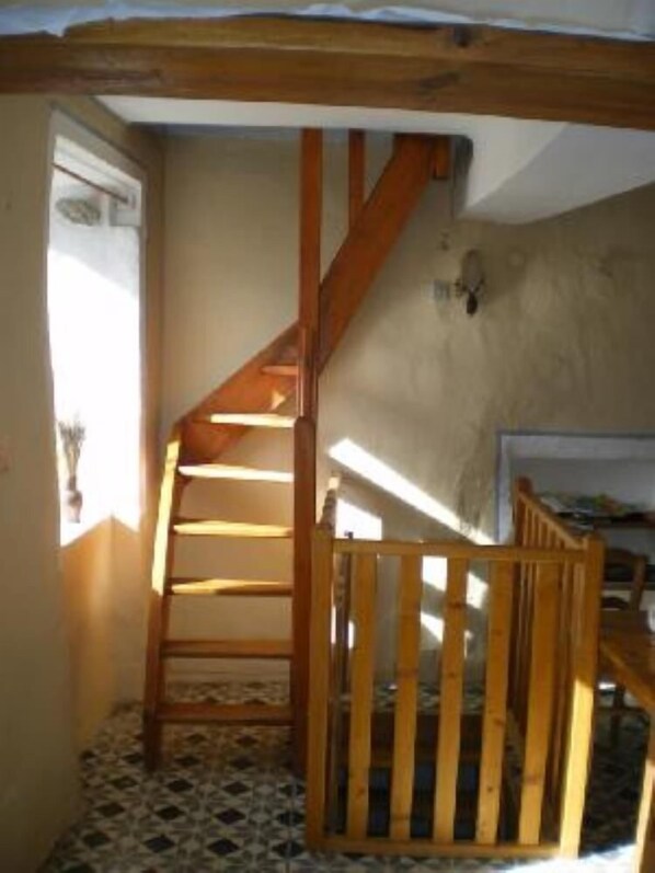 A wooden staircase with a handrail leading to a landing, a tiled floor, and a window with a view of the outside.