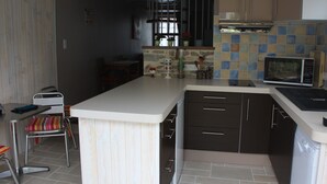 Una cocina compacta con una isla central, armarios oscuros y un microondas.