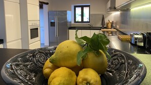 Una cocina moderna con armarios blancos, un refrigerador de acero inoxidable y un tazón decorativo negro con limones.