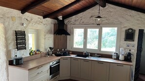 Eine Küche mit Holzboden, einer integrierten Weinstauflage, einem Herd und einem Spülbecken.
