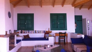 Een gezellige woonkamer met een houten plafond, een bank, een salontafel en een boekenplank vol boeken.