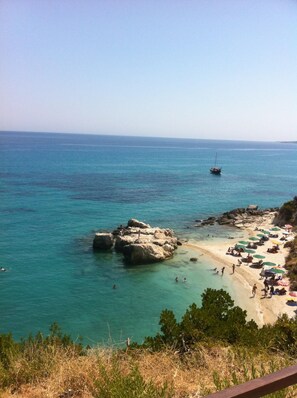 Ein Strand mit klarem türkisblauem Wasser, Felsen und einem sandigen Ufer.