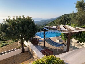 Un espace piscine agrĂ©mentĂ© dâune pergola, dâun hamac et offrant une vue sur le paysage.