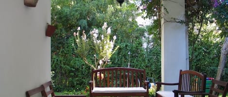 Une terrasse avec un banc en bois, deux chaises et une lanterne suspendue.