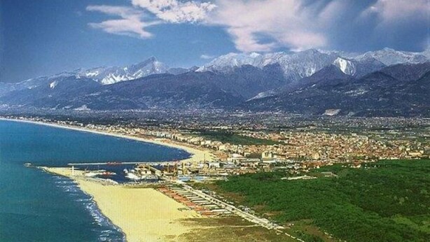 Una città costiera con una spiaggia e montagne sullo sfondo.