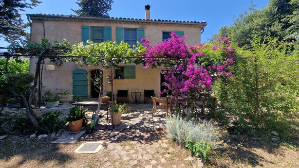 Una casa rústica con un patio jardín, una mesa pequeña y sillas.