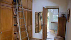Una habitación con armarios de madera, una escalera, un espejo y una cesta de mimbre.