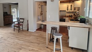 Una cocina moderna con encimera de madera, taburetes de bar y una zona de comedor con una silla y una mesa.